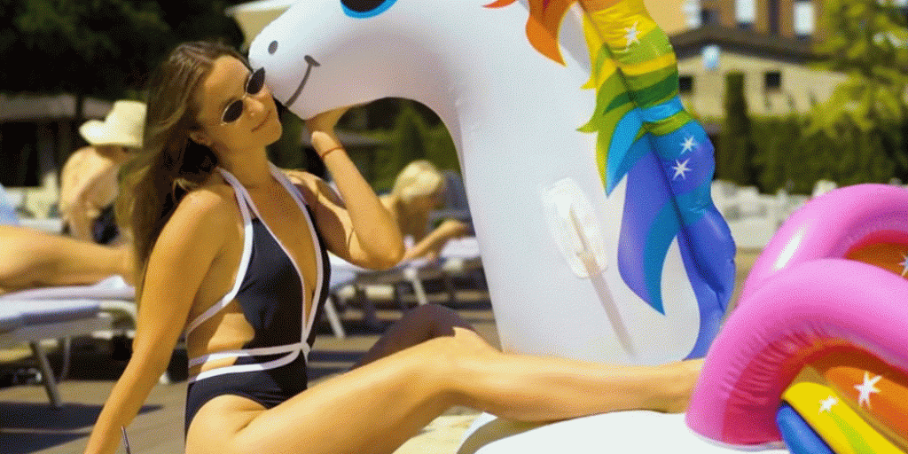 Traveler relaxing by pool with inflatable unicorn green travels holiday lifestyle