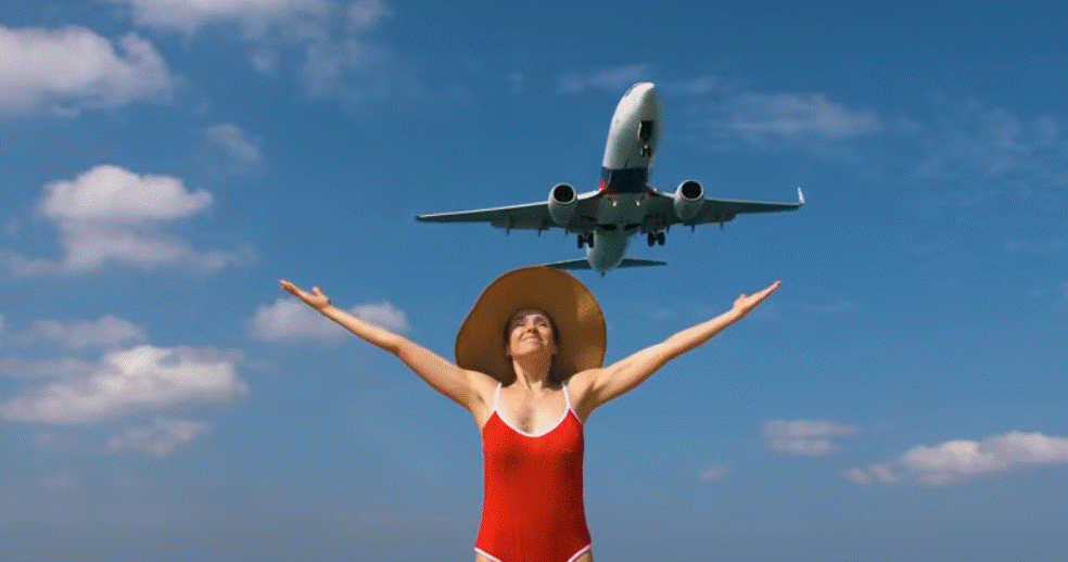 Traveler enjoying flight overhead with open arms under blue sky green travels concept.