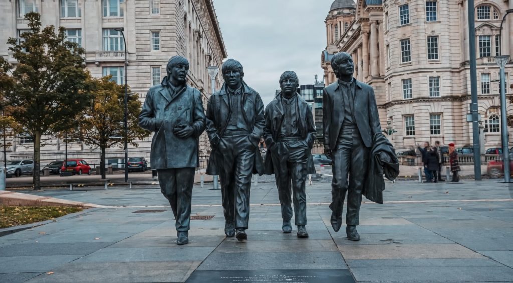 Statue of The Beatles at Pier Head in Liverpool, featuring the iconic band walking along the historic waterfront with city architecture in the background
